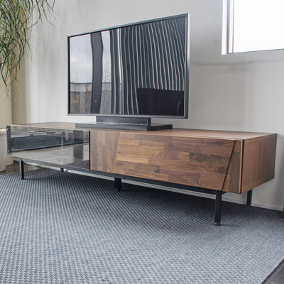 ウォールナット無垢材の木目を精巧に組み替えた前板と、ダークグレーのガラス扉の組み合わせが特別な存在感を演出するテレビボードです。